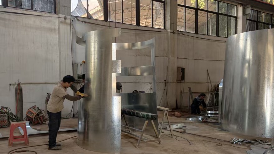 worker roll bending large steel plate in the playground equipment workshop खेल के मैदान उपकरण कार्यशाला में बड़ी स्टील प्लेट को मोड़ने वाला कार्यकर्ता रोल